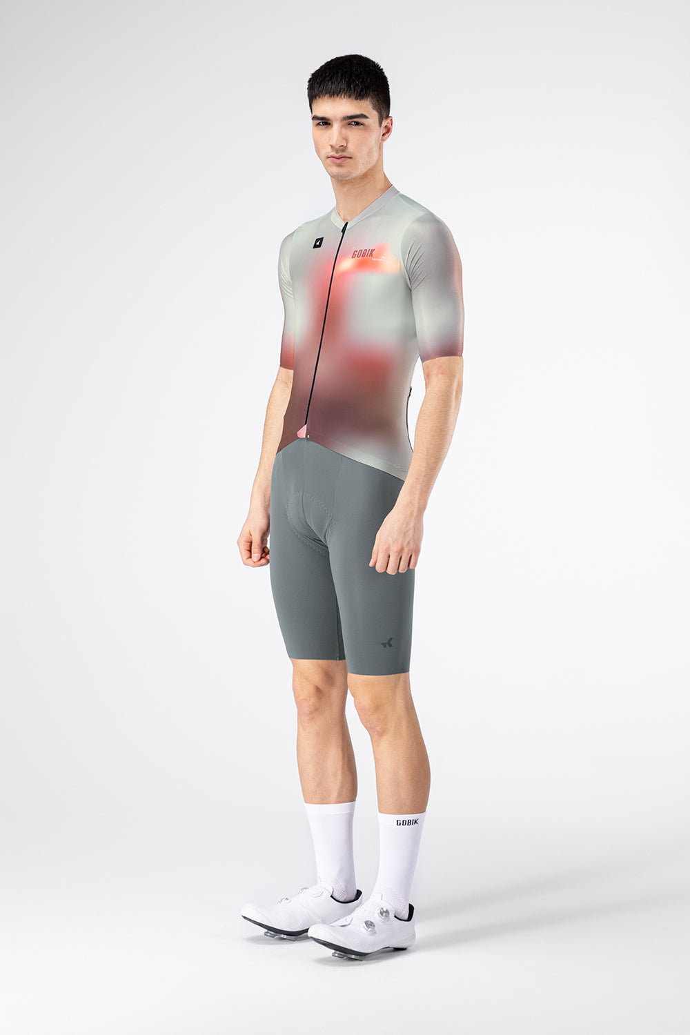 Three-quarter side view of male model in Gobik Attitude 2.0 Flank jersey and gray bib shorts