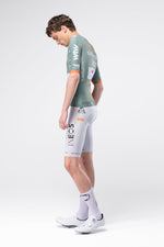 Male cyclist model wearing Gobik INEOS Grenadiers Raeactive jersey in sage green with white bib shorts