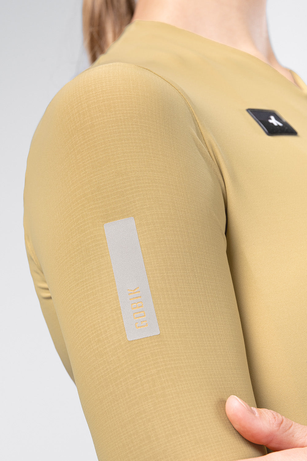 Detail shot of Gobik Avalon Jersey sleeve showing reflective Gobik branding strip in Keemun color