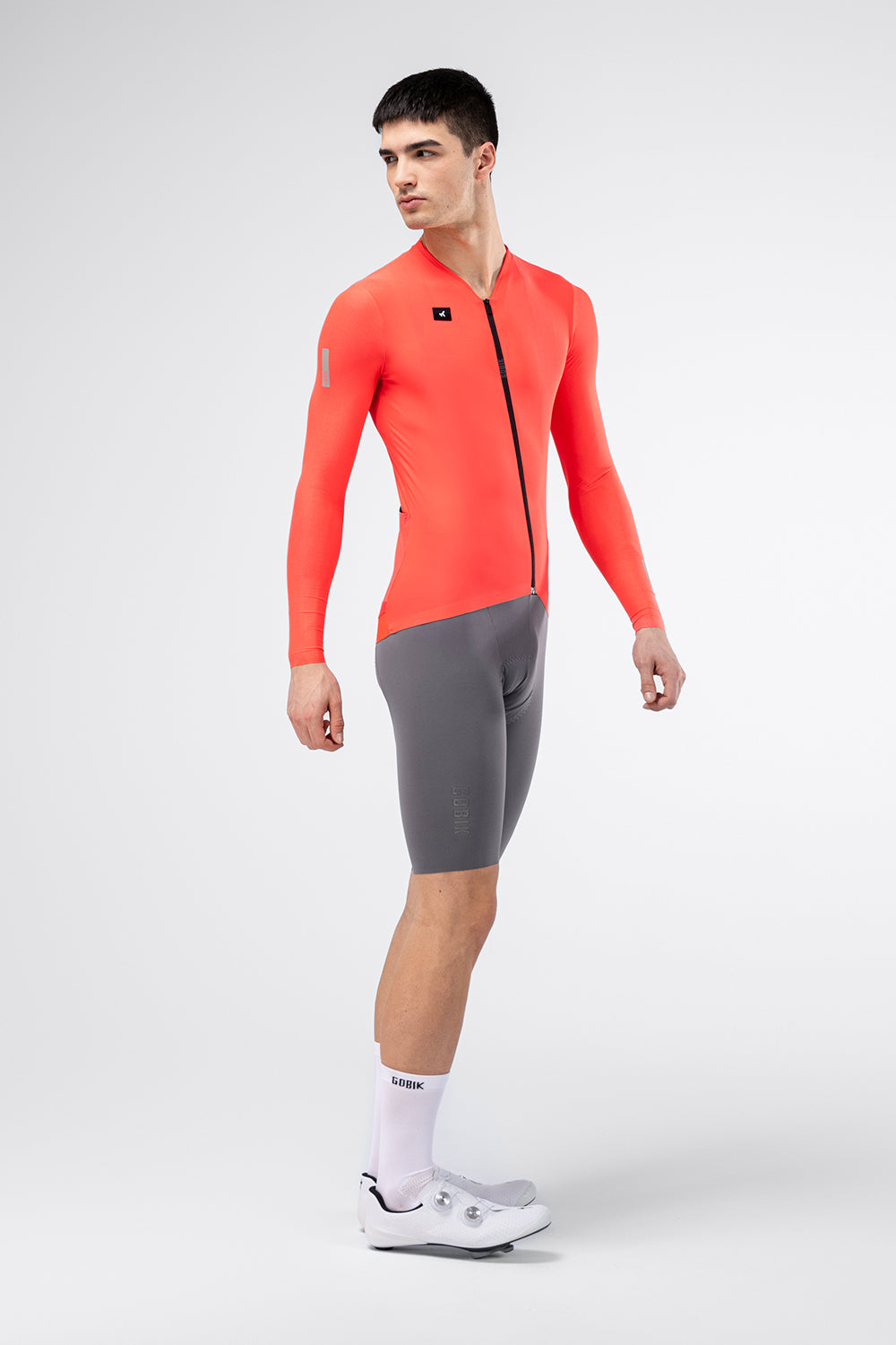 Gobik Avalon Long Sleeve Jersey in Lava color, male model side view with gray shorts