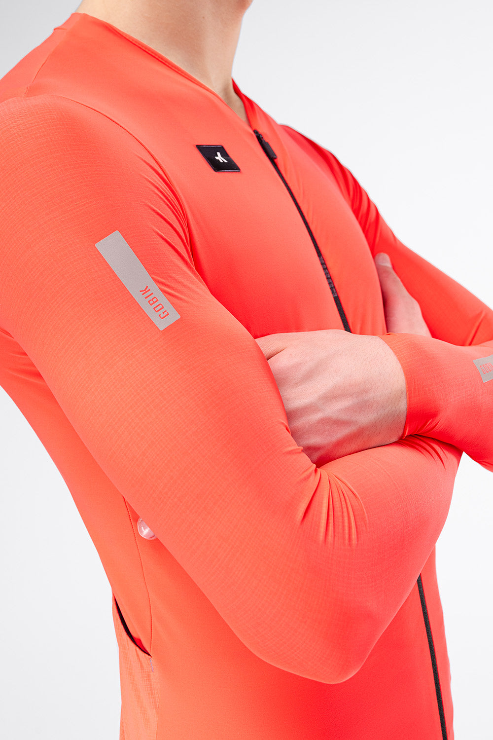 Close-up of Gobik Avalon Long Sleeve Jersey sleeve with reflective Gobik logo detail in Lava