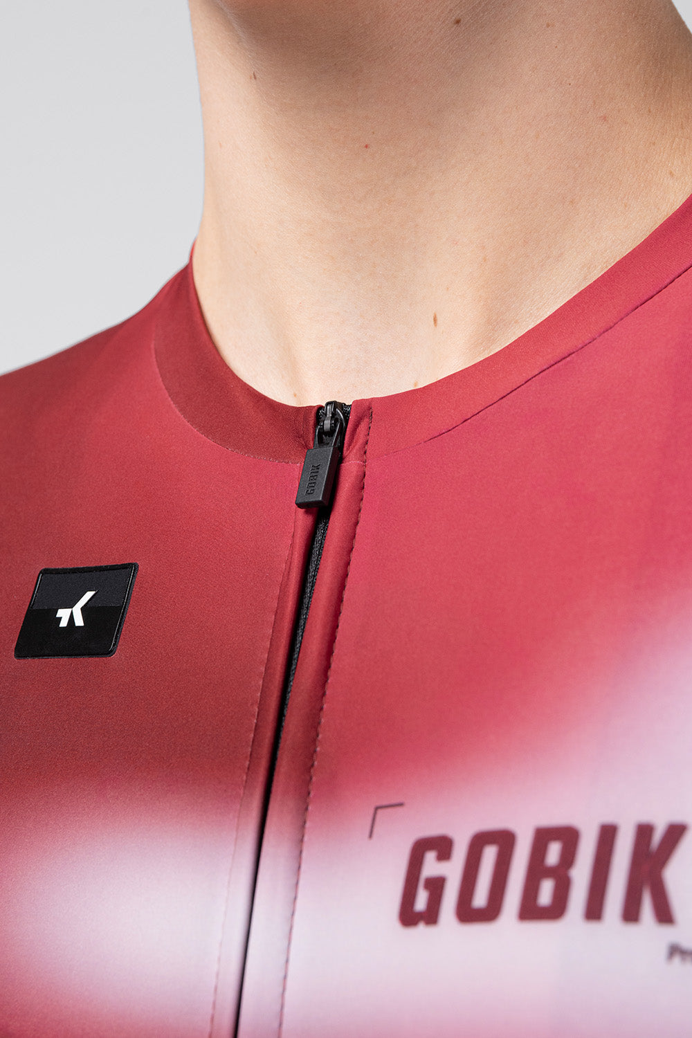 Close-up of Gobik Vanquish jersey zipper and chest detail in Monarch red colorway with brand logo