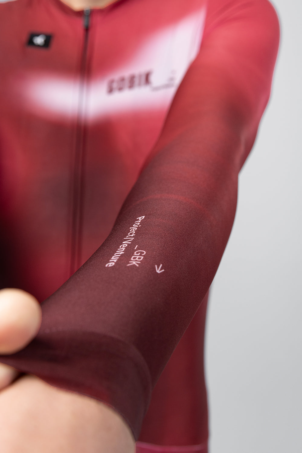 Close-up of Gobik Vanquish jersey sleeve detail showing GBK Project Venture text in Monarch red