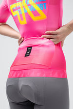 Gobik CX Pro cycling jersey in neon pink Drip colorway shown from rear on female model