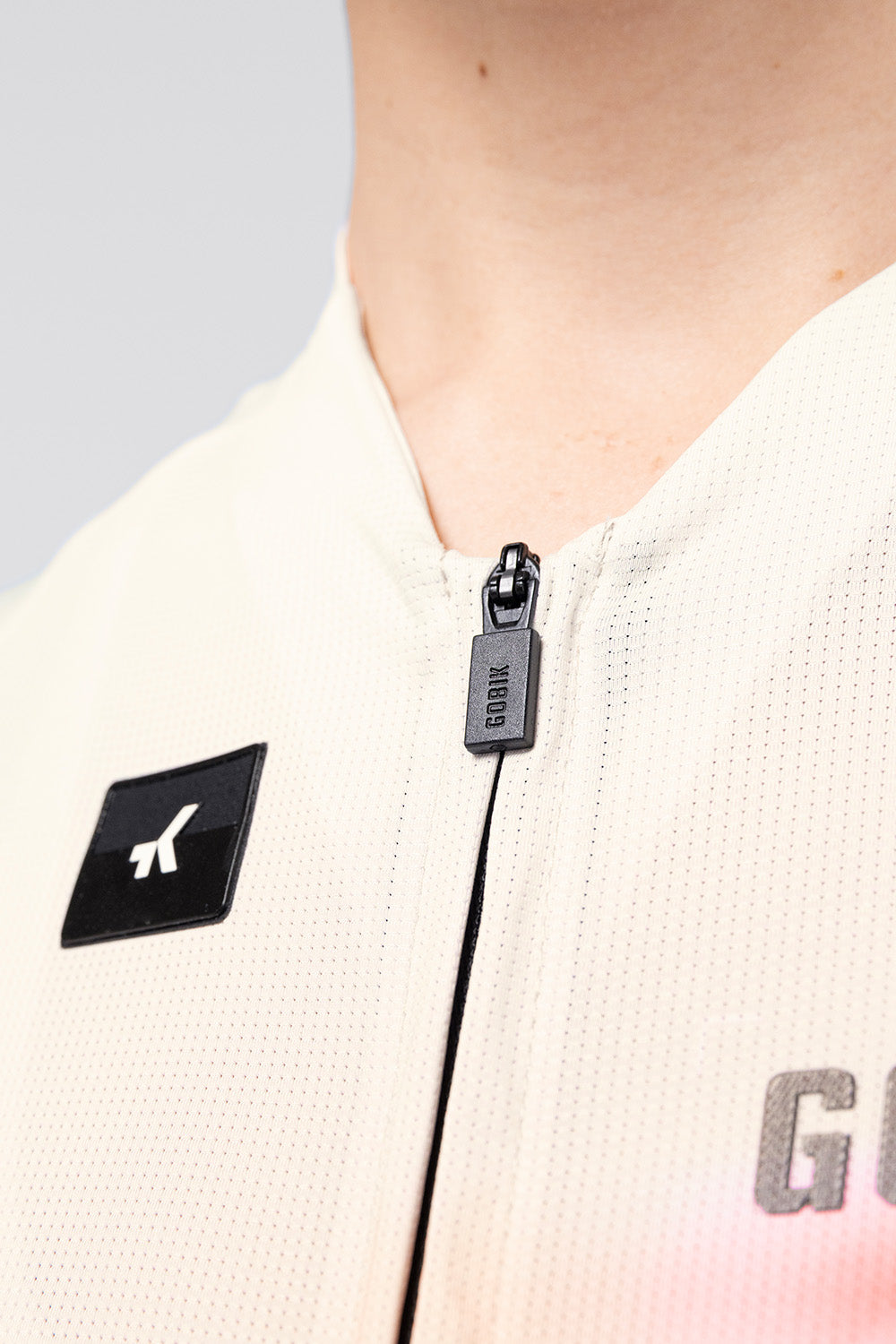 Close-up detail of Gobik CX Pro 4.0 jersey zipper pull and chest logo on almond fabric
