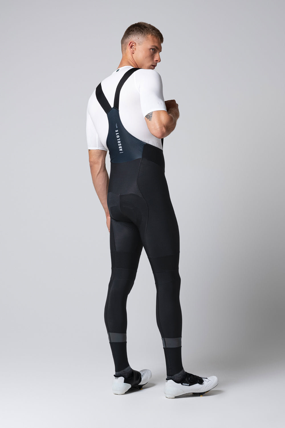 Man wearing black Gobik cycling bib shorts with suspenders, rear view