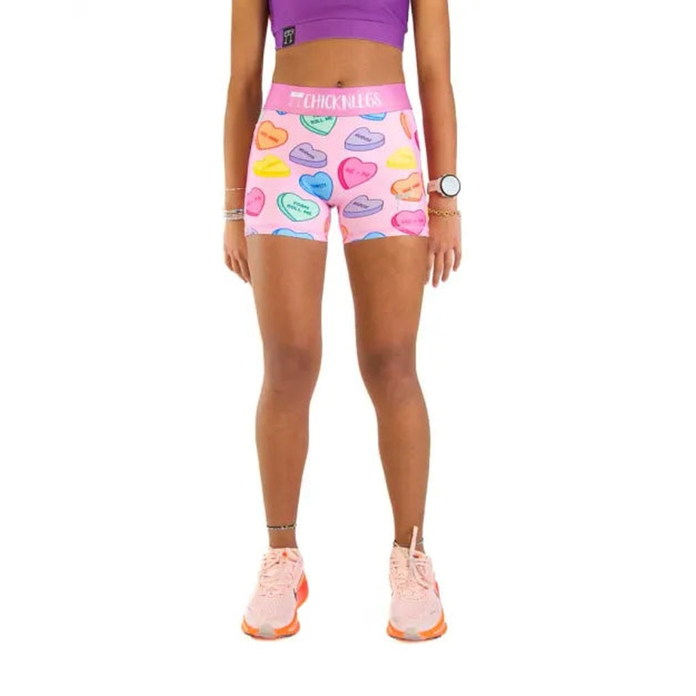 Woman wearing pink compression shorts with colorful candy hearts pattern by ChicknLegs