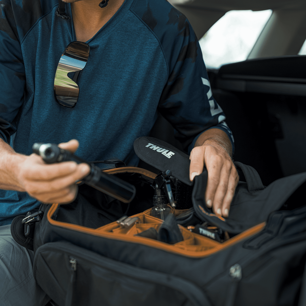 Person packing Thule Roundtrip bike duffel bag in car with phone