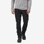 Man wearing black Patagonia trail pants with gray long-sleeve shirt and hiking boots