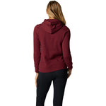 Back view of woman wearing cranberry Fox Racing pullover fleece hoodie with black pants