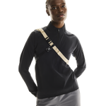 Model wearing On Sling Pack 9L in Biscuit and Black colorway over black athletic jacket