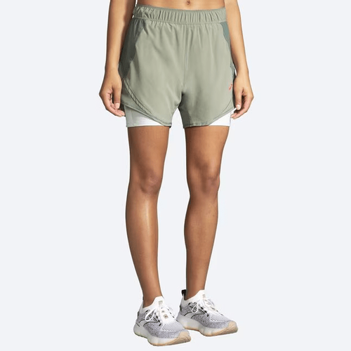 Woman wearing Brooks Chaser 5 inch 2-in-1 running shorts in sage green color