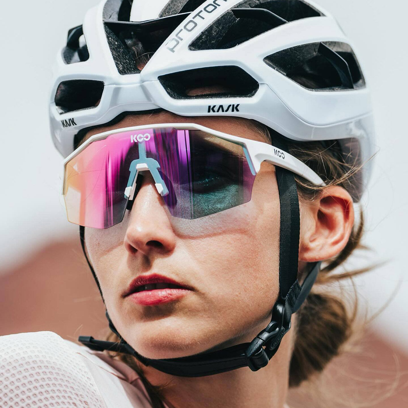 KOO Alibi cycling sunglasses in white with photochromic fuchsia lenses worn by cyclist