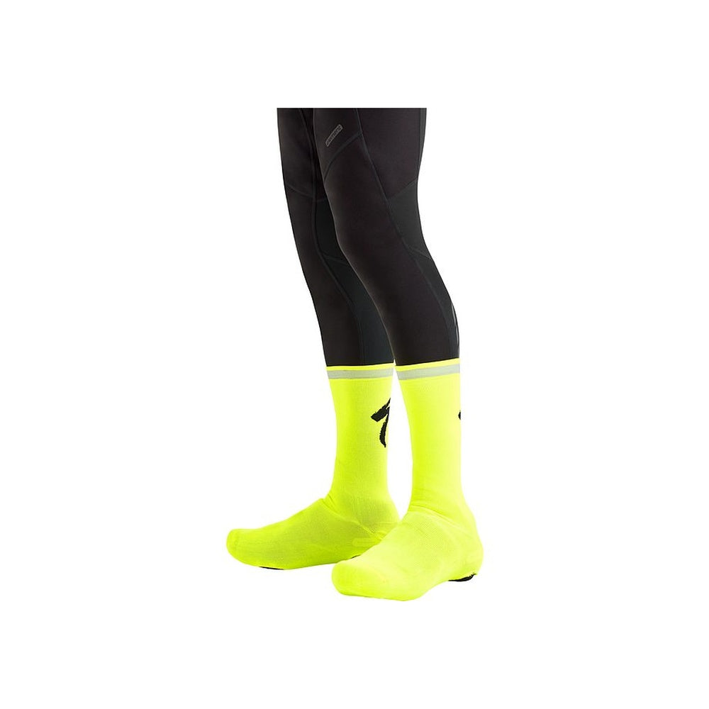 Specialized Reflect Overshoe Socks in neon yellow worn on both feet with black cycling tights