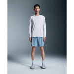 Man wearing white On Core Long-T shirt with blue shorts in studio setting
