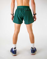 Back view of man wearing forest green athletic shorts with split sides