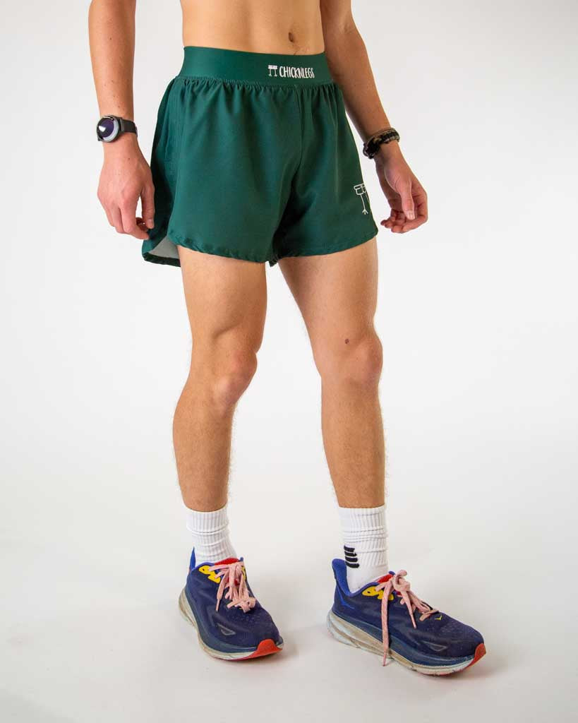 Model wearing ChicknLegs forest green 4-inch half split running shorts with elastic waistband