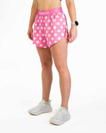 Woman wearing pink polka dot athletic shorts with ChicknLegs branding on waistband