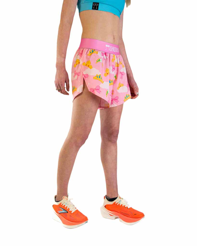 Woman wearing pink ChicknLegs split running shorts with princess tiara pattern and teal sports bra