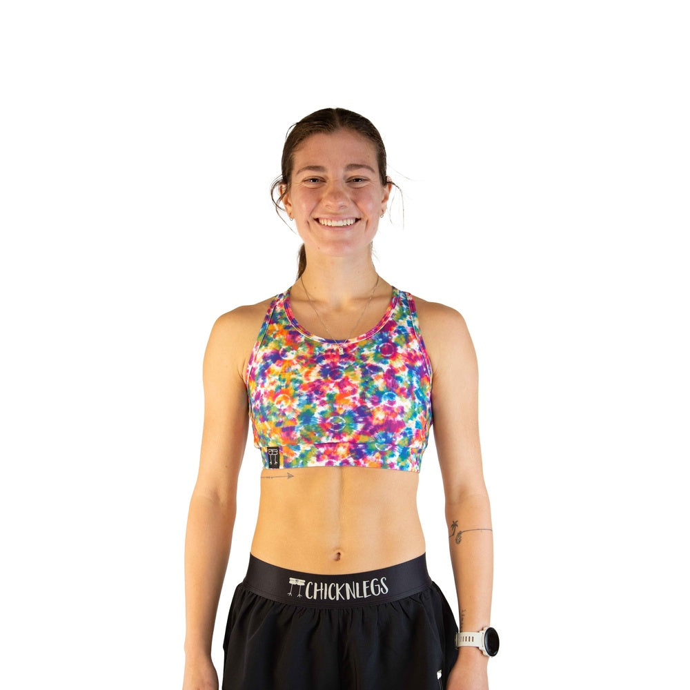 Woman wearing ChicknLegs tie-dye sports bra in vibrant rainbow colors