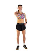 Woman wearing ChicknLegs tie-dye sports bra with black shorts pointing at camera