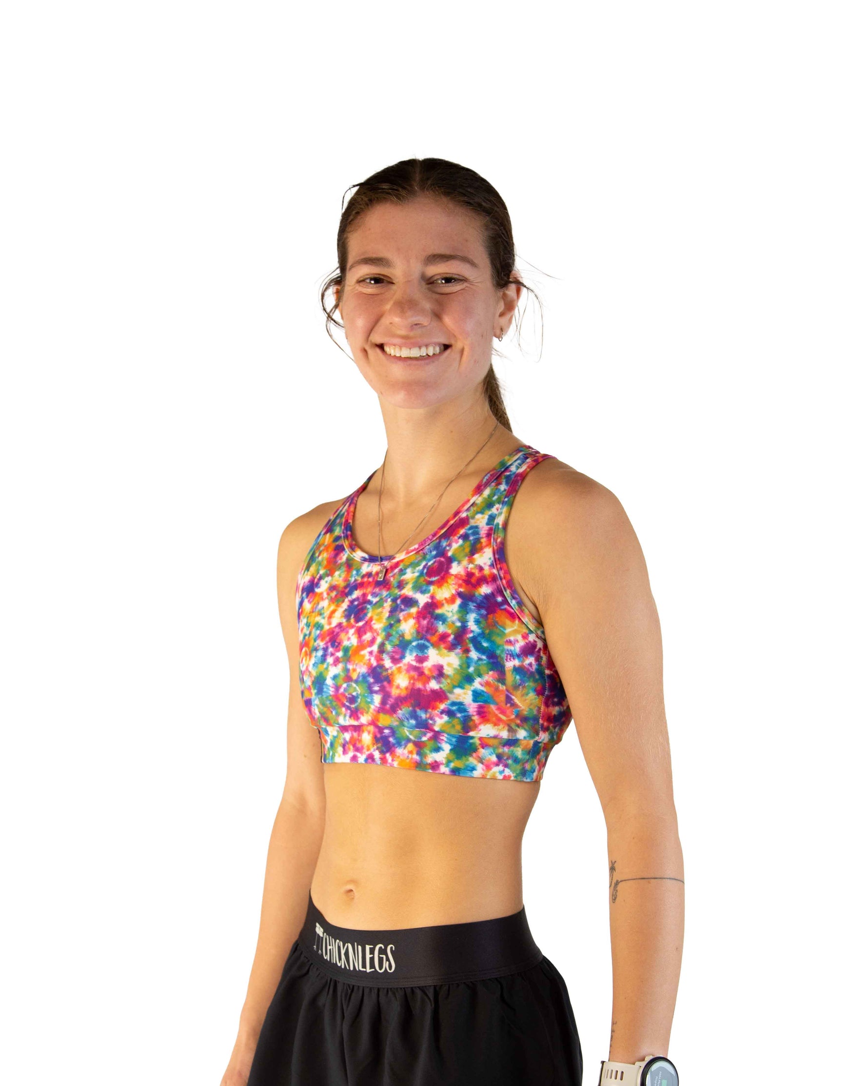 Woman wearing colorful tie-dye sports bra with rainbow splatter pattern