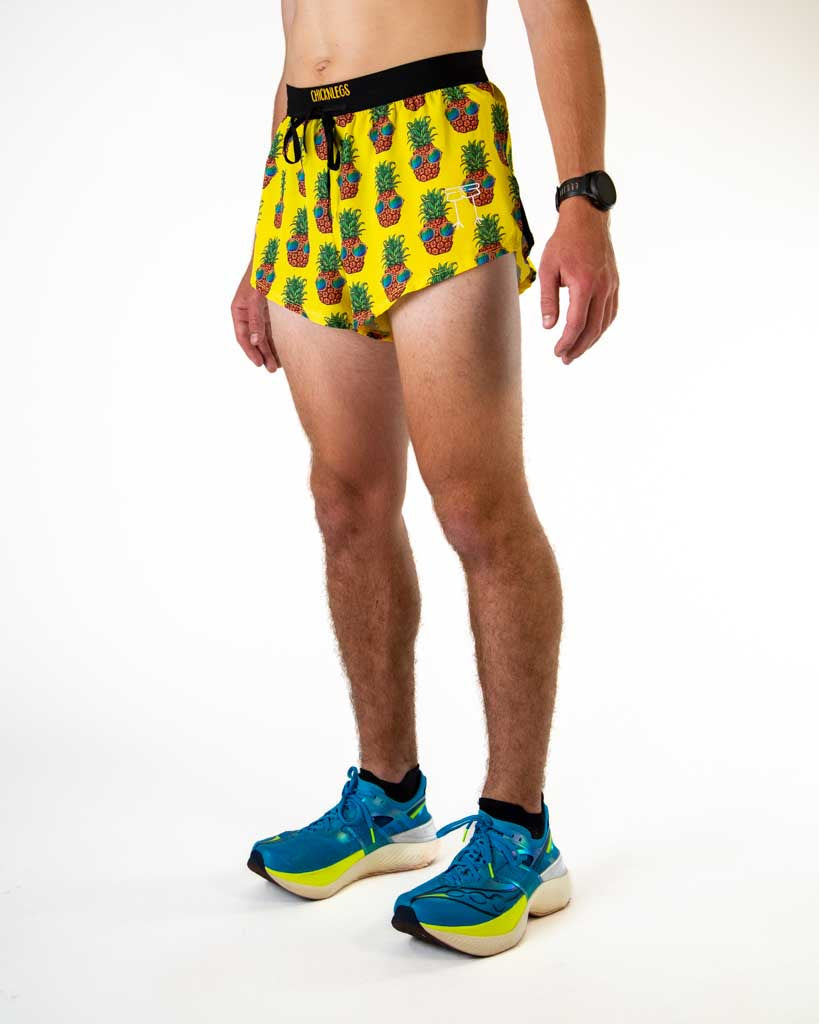 ChicknLegs men's 2-inch split running shorts in yellow Pineapple Express pattern with blue sneakers