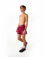 Shirtless male model wearing maroon ChicknLegs running shorts in studio setting