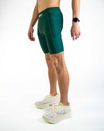 Man wearing forest green athletic compression shorts with running shoes against white background