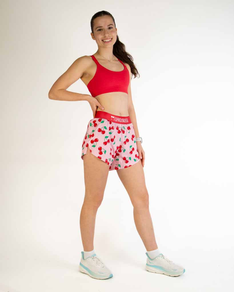 Female model wearing ChicknLegs 4-inch split running shorts in cherry print pattern
