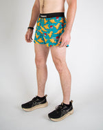 Man wearing ChicknLegs turquoise shorts with orange chicken nugget pattern and black waistband