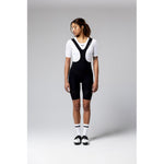 Woman wearing black Gobik Ultralite bib shorts with white jersey in studio setting