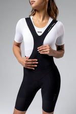 Woman wearing black Gobik Ultralite bib shorts with white mesh jersey