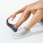 Person wearing gray Feetures Elite invisible socks with white running shoes