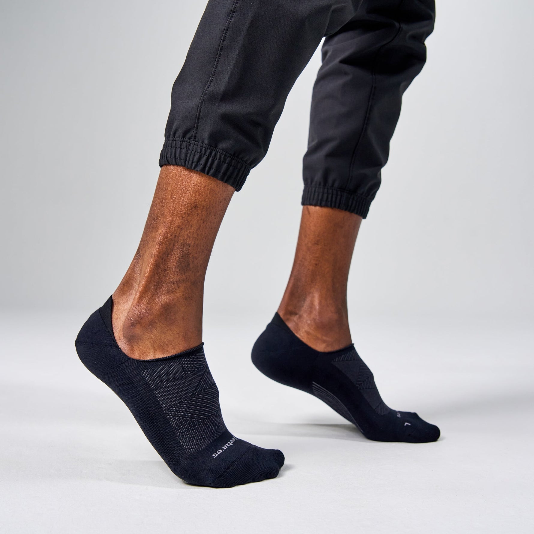 Black Feetures Elite Light Cushion Invisible no-show socks on model's feet