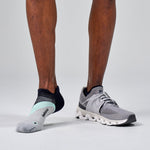 Feetures Elite Light Cushion Tab socks in grey with running shoes on model's feet