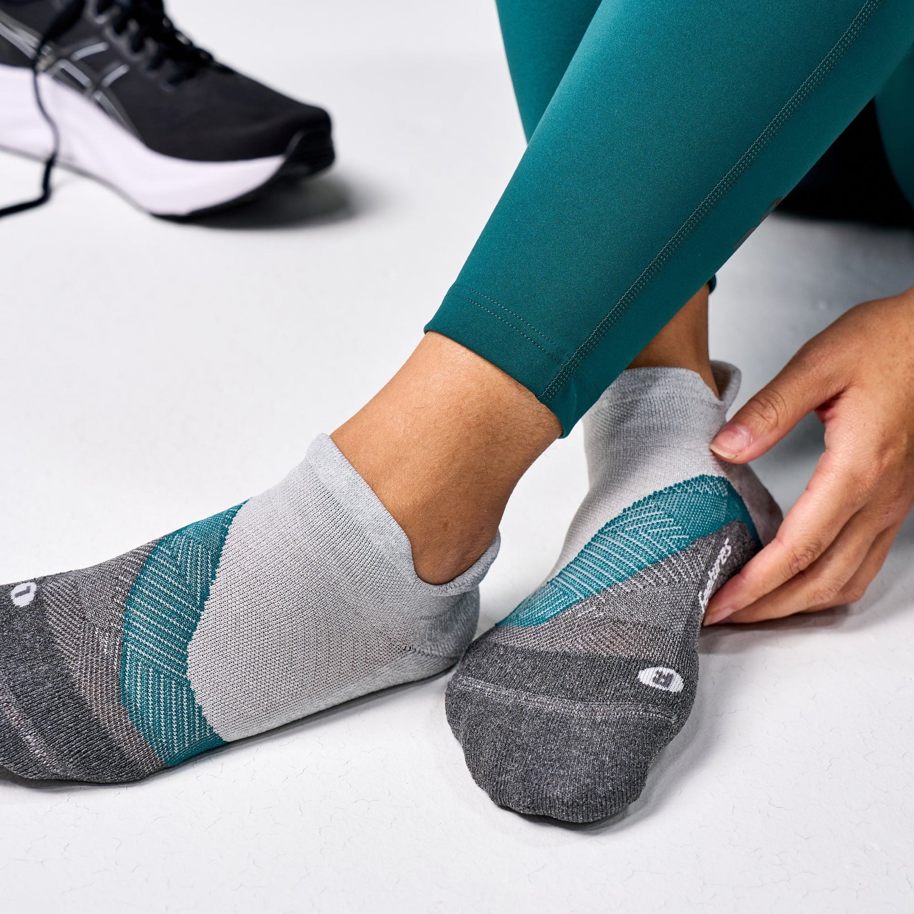Feetures Elite Light Cushion Tab socks in gray with teal accents on feet