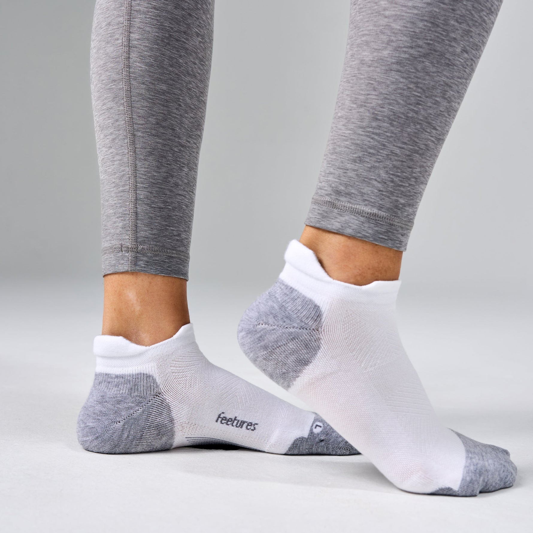 Feetures Elite Max Cushion Tab socks in white and grey worn with grey leggings