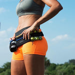 Female athlete wearing Fitletic black hydration running belt with gels outdoors in orange shorts