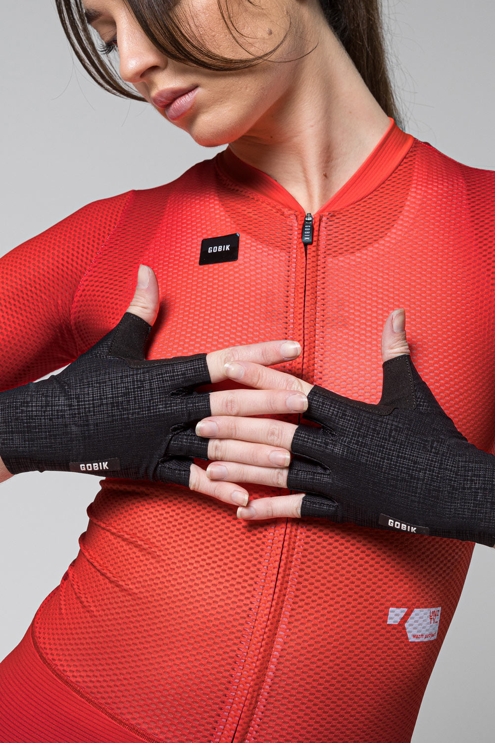 Model wearing black Gobik cycling gloves with fingerless design and brand logo