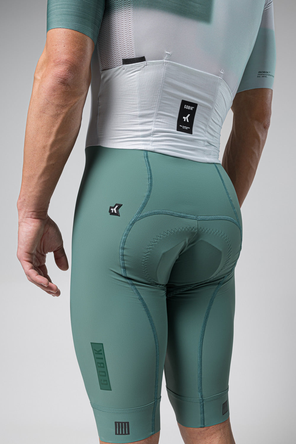 Gobik Brooklyn Aerosuit in sage green showing rear view with cycling shorts