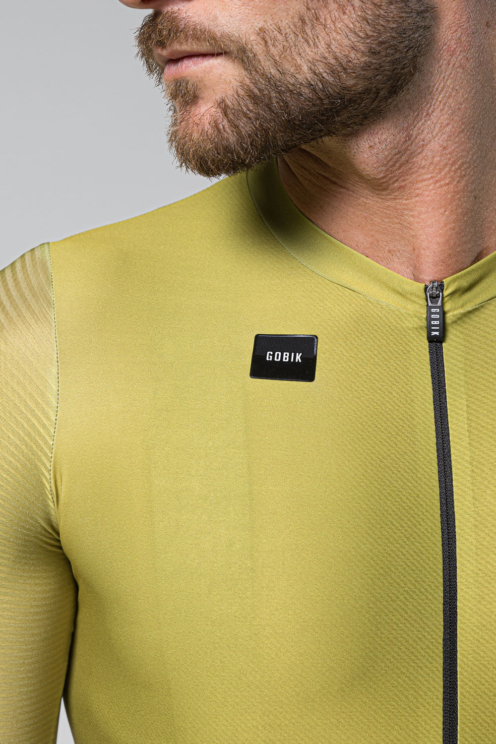 Man wearing olive green Gobik cycling jersey with black zipper and logo patch