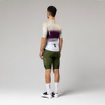 Male cyclist wearing Gobik CX-Pro jersey in Teaberry colorway with olive green bib shorts, rear view