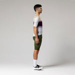 Male cyclist wearing Gobik CX-Pro jersey in Teaberry colorway with olive green bib shorts, side view