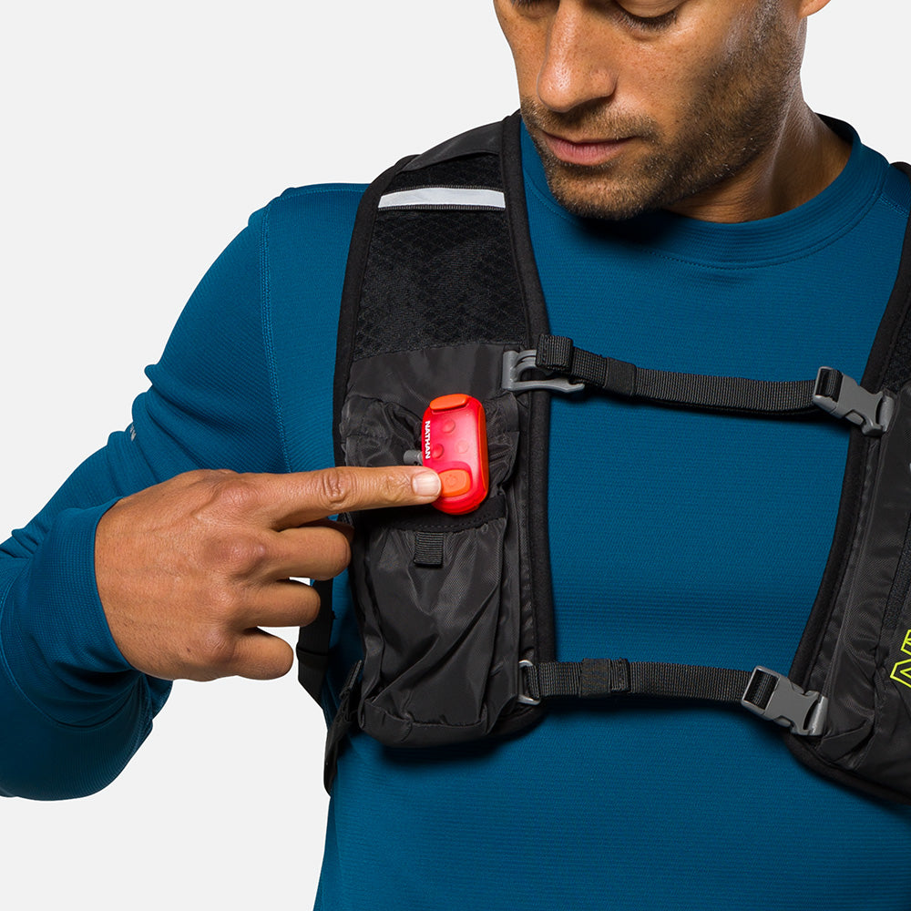 Man wearing chest pack demonstrating red Nathan LED safety light clip attachment