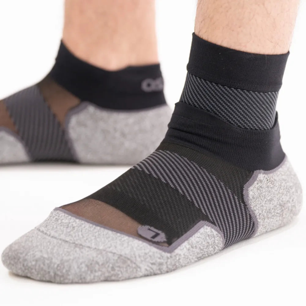 OS1ST FS6 Performance Foot Sleeves in black worn on feet showing compression zones