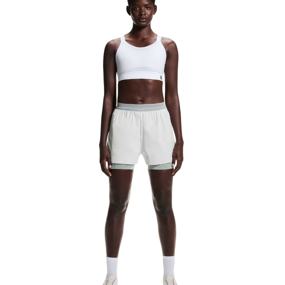 On Running Performance Bra in white paired with light green shorts, front view on model