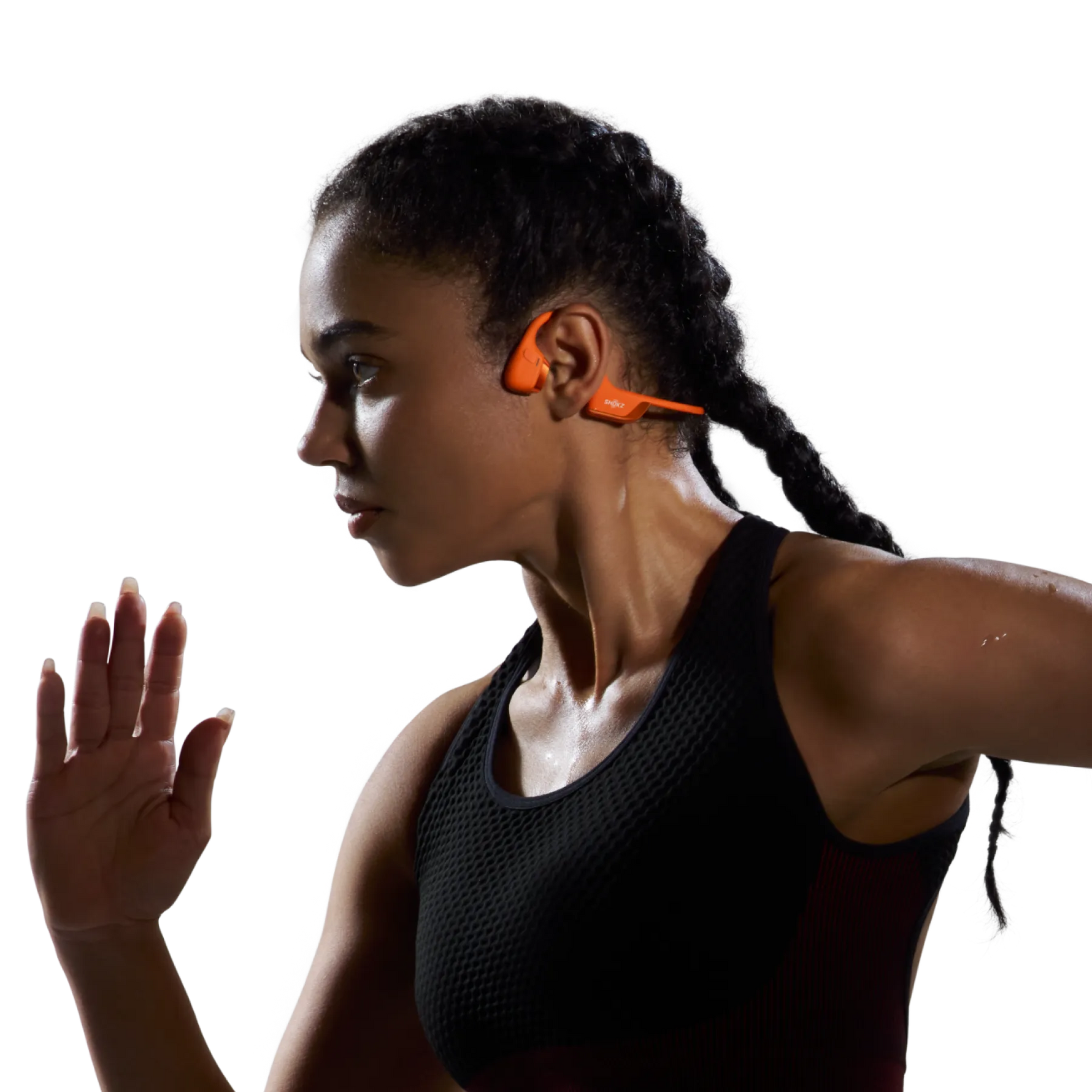 Woman wearing orange Shokz bone conduction headphones during workout, showing open-ear design