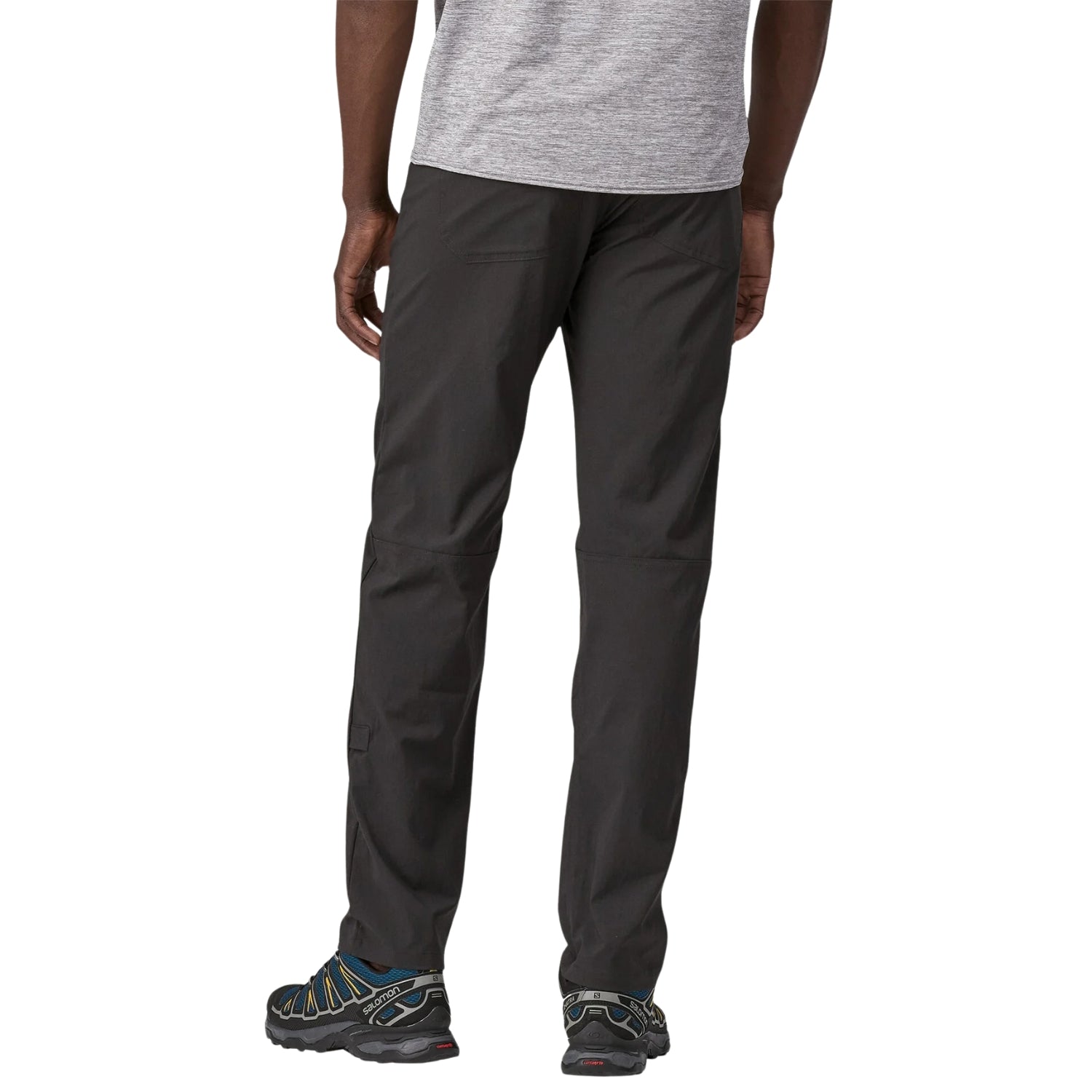Man wearing black Patagonia Quandary convertible pants with hiking shoes on white background