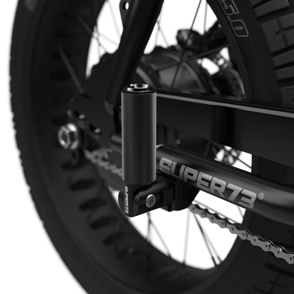 Black Super73 folding peg attached to bicycle frame showing textured grip surface